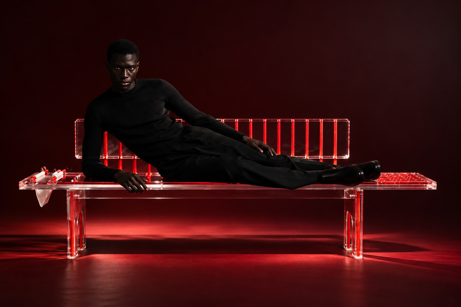 Portrait on an illuminated transparent bench against a red backdrop